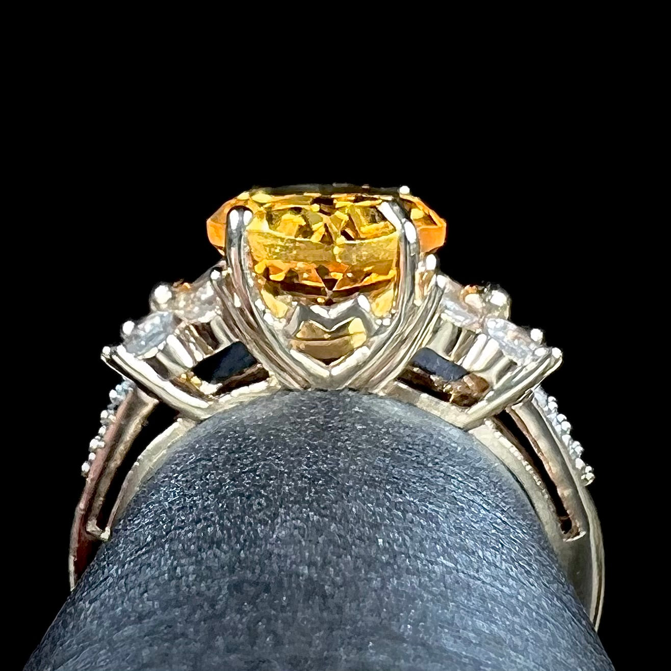 A cushion cut citrine set in a yellow gold ring with four round white sapphires and two diamonds on each side.