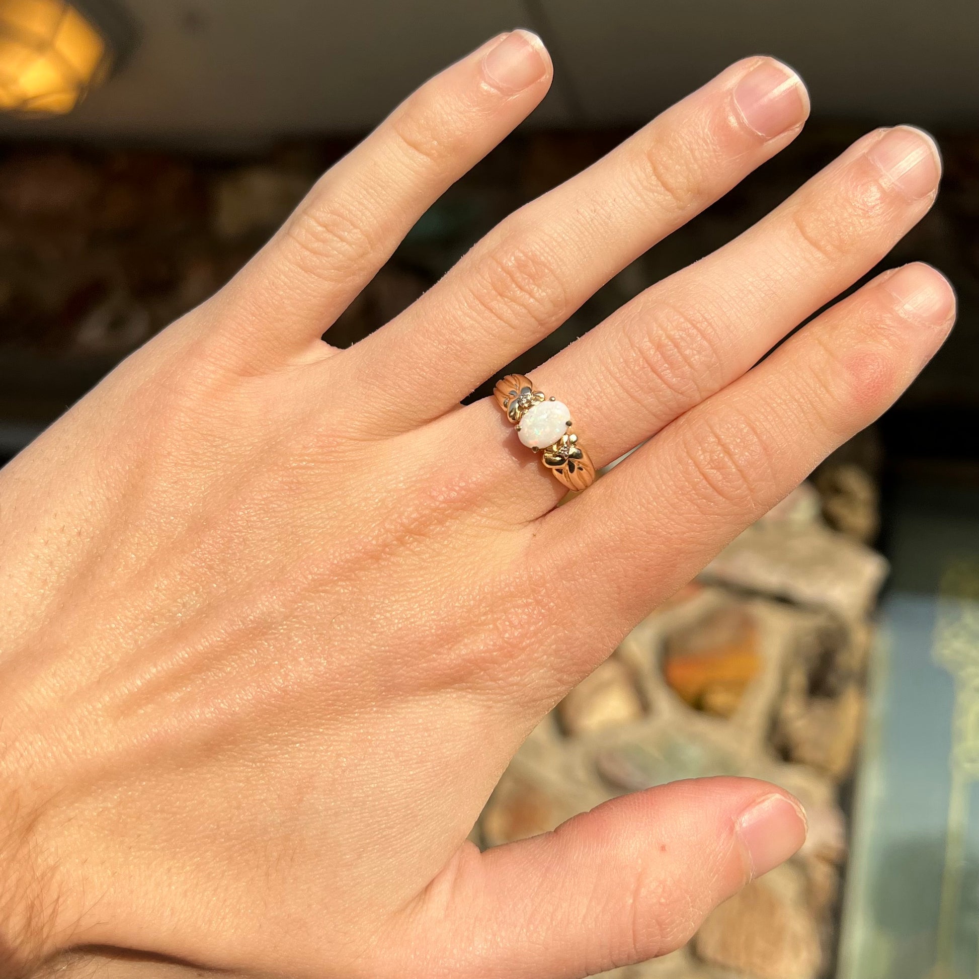 A ladies' yellow gold white crystal opal and diamond ring.  The opal is prong set.