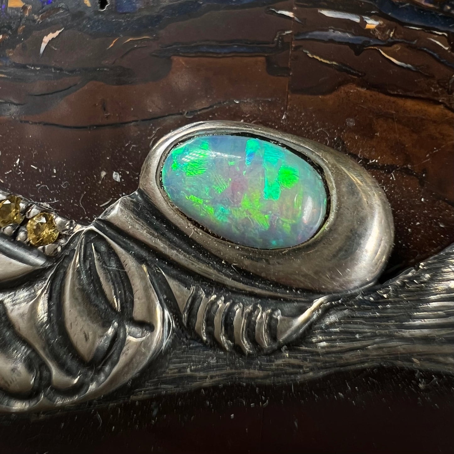 A stone box made from Koroit, Australian boulder opal featuring the motif of a dragonfly and cricket made from sterling silver, set with yellow diamonds, an emerald, and a crystal opal.