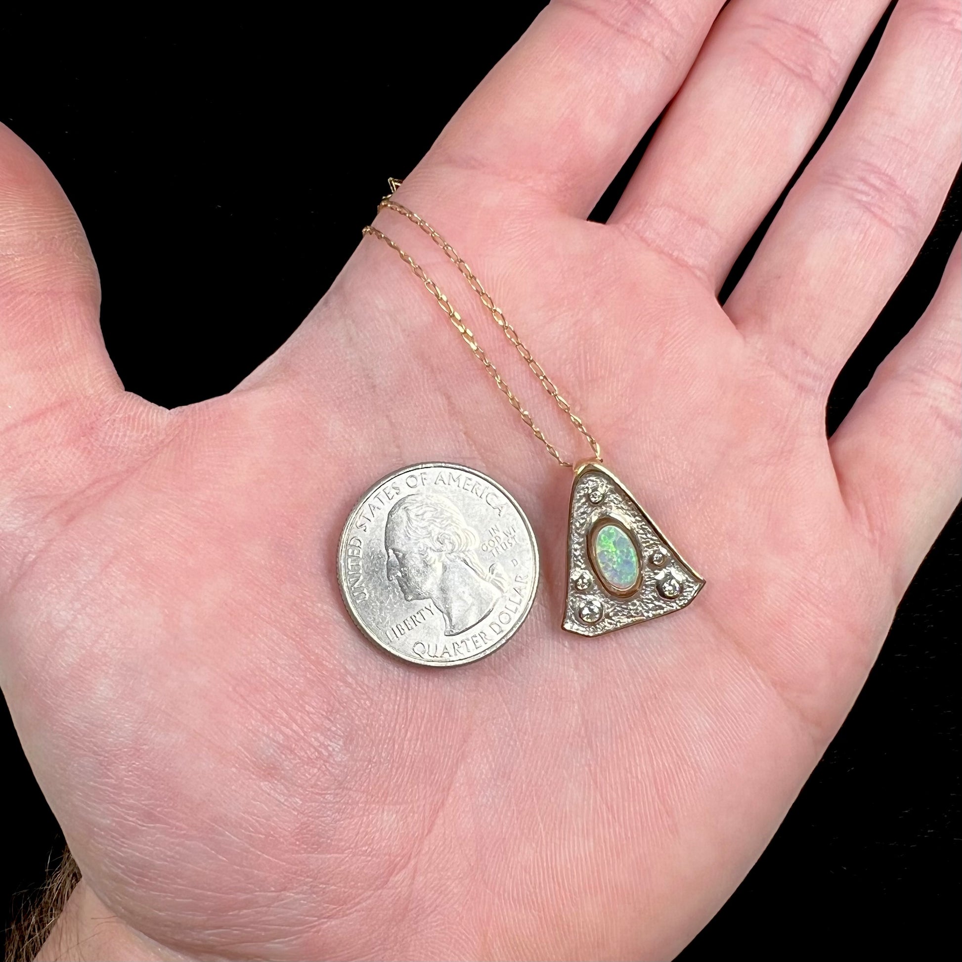 A triangular gold pendant set with five round diamonds and a white crystal opal with green fire.