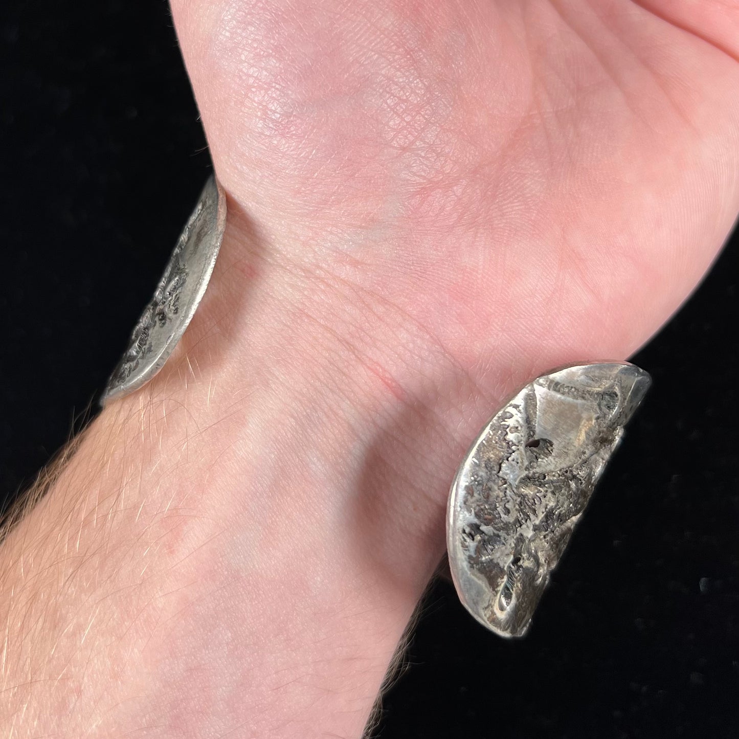 A men's sterling silver cuff bracelet infused with copper and set with a green turquoise stone from Carico Lake, Nevada.