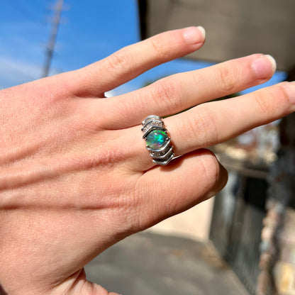 A white gold ring set with a Lightning Ridge black opal and baguette cut diamonds.