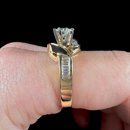 A ladies' yellow gold engagement ring set with a 0.77ct oval cut diamond and baguette cut diamond accents.