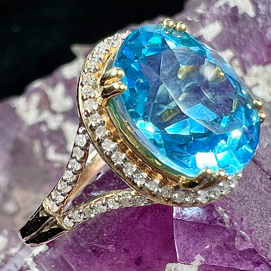 An oval cut Swiss blue topaz and diamond pave split shank ring in yellow gold.