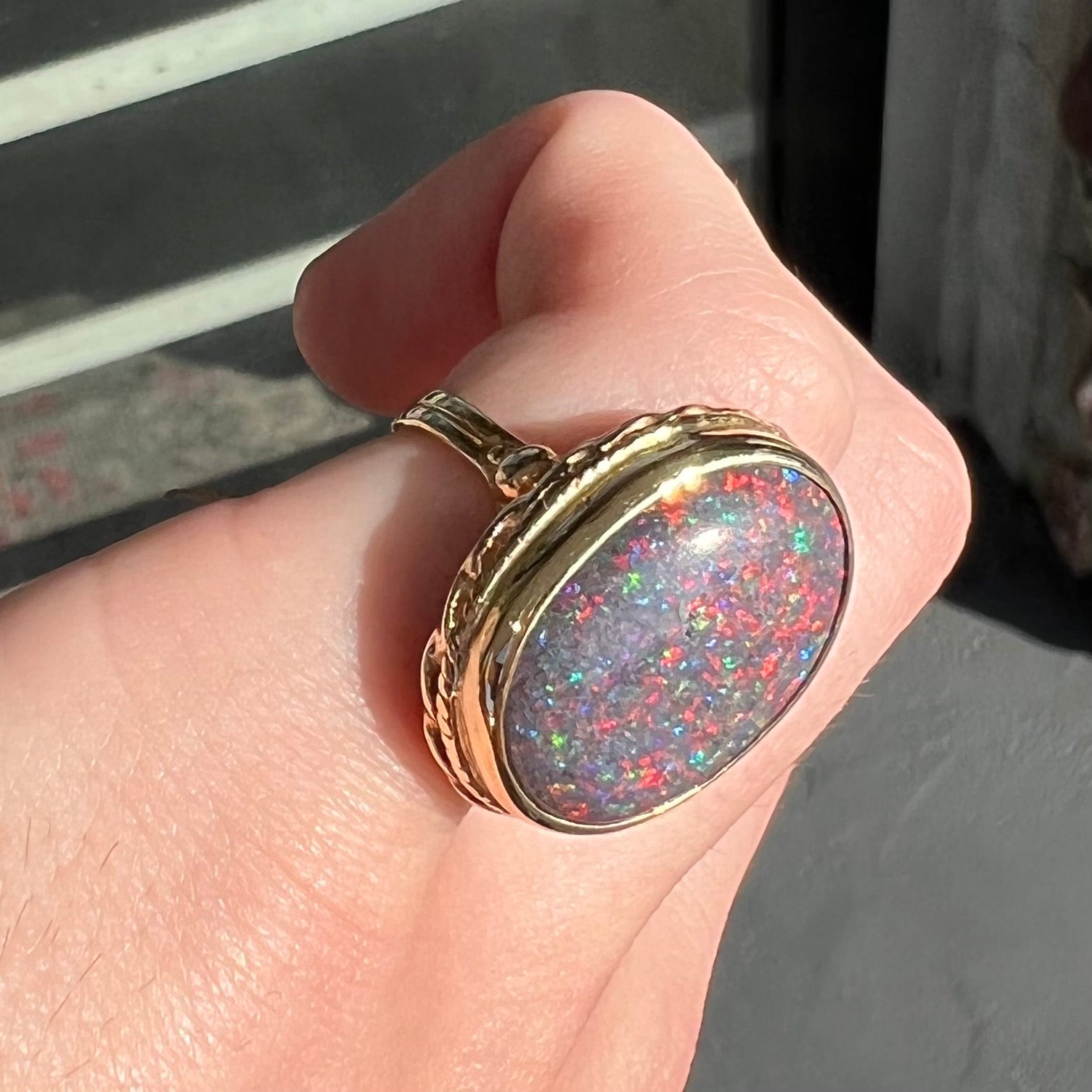 A bright black Andamooka opal that displays a pinfire pattern set in a vintage-style yellow gold bezel ring.