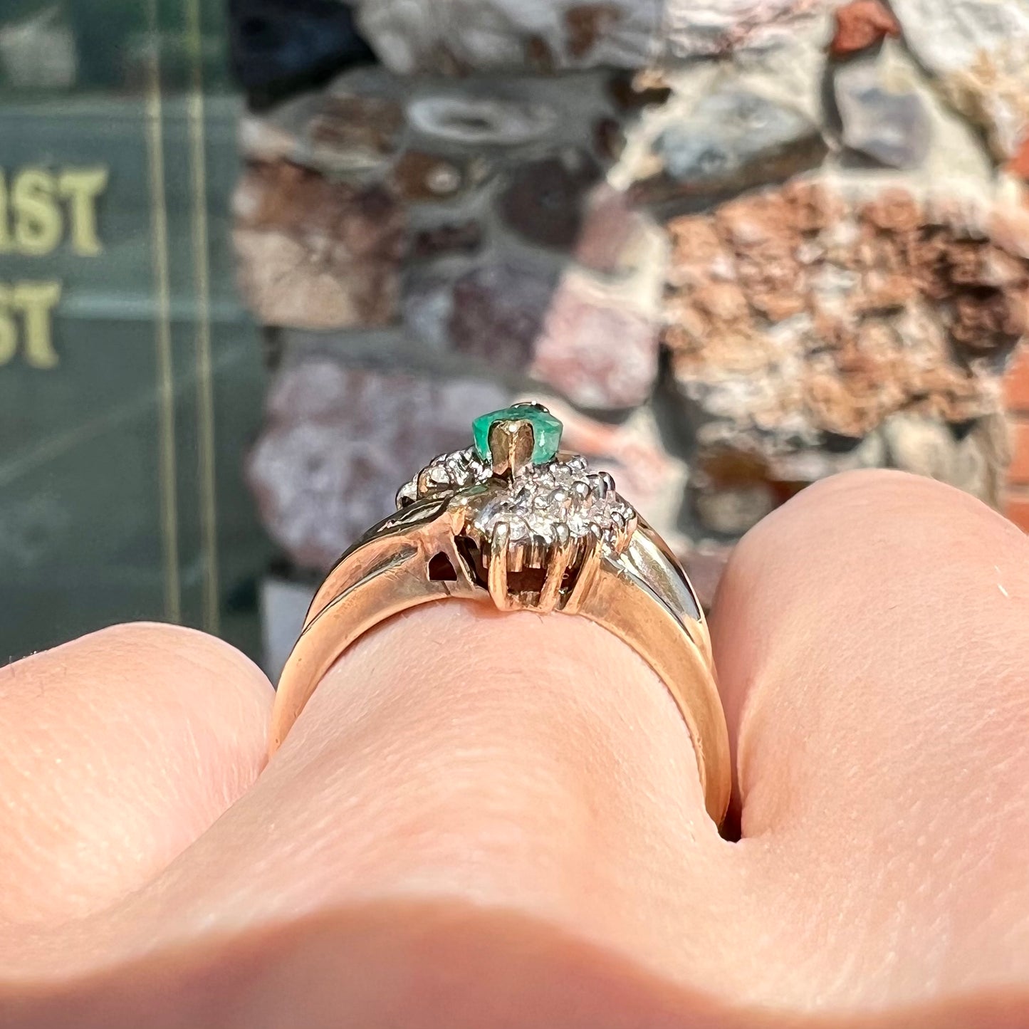 A yellow gold marquise cut emerald and diamond ring.  The diamonds are prong set round cuts and channel set baguette cuts.