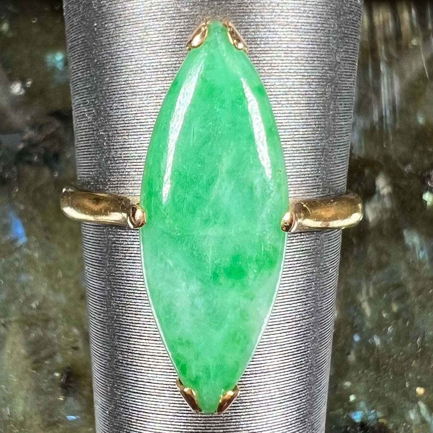 A 22 karat yellow gold solitaire ring set with a marquise cabochon cut green jadeite.