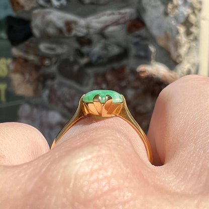 A 22 karat yellow gold solitaire ring set with a marquise cabochon cut green jadeite.