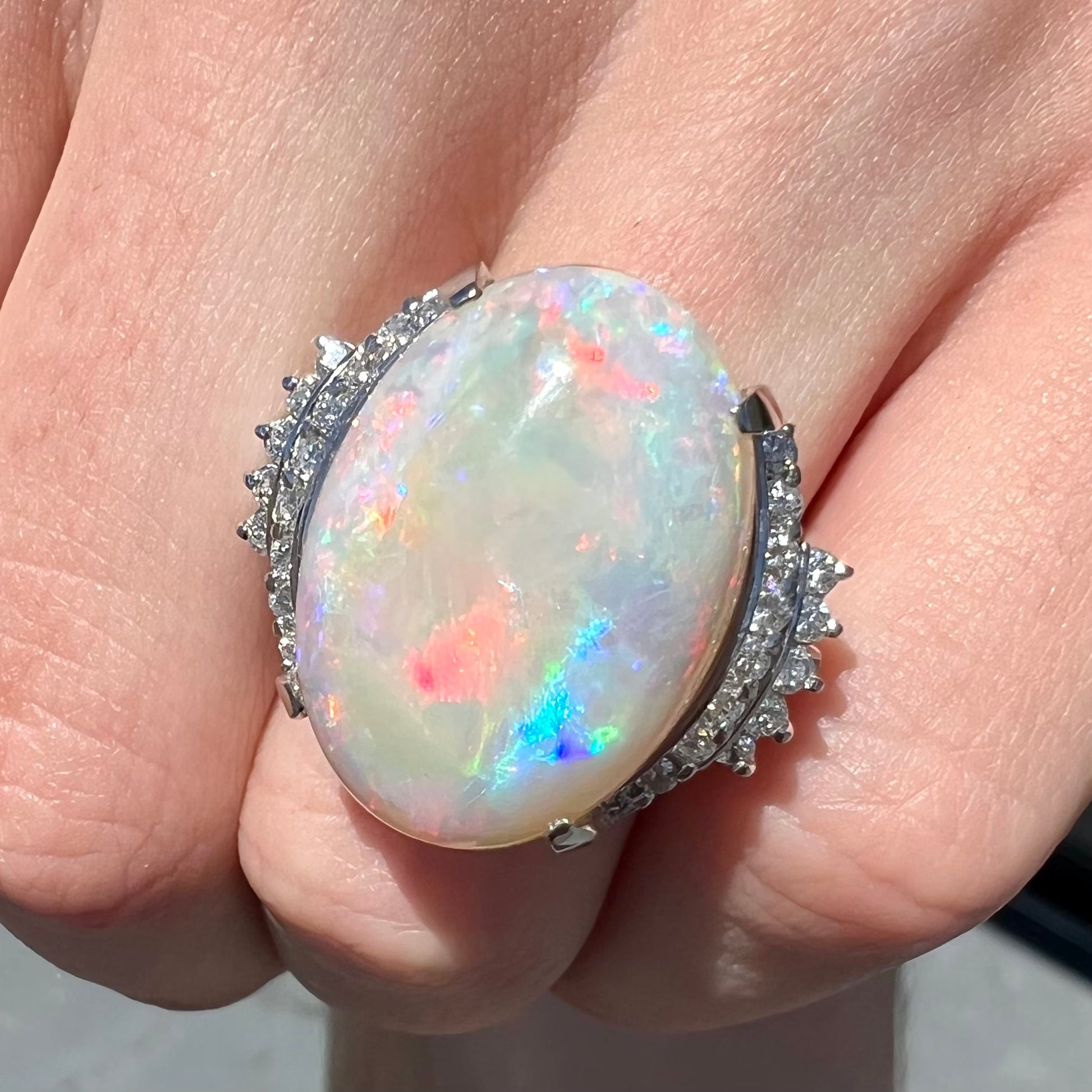 An oval cabochon cut Coober Pedy, Australian opal prong set in a platinum ring with round cut diamonds.