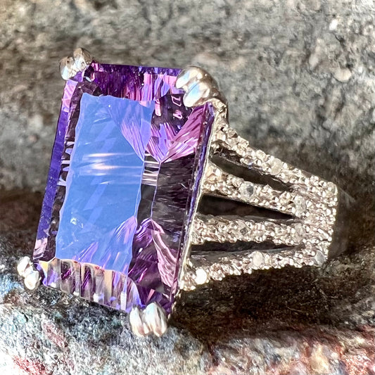 A white gold ladies ring set with an emerald laser cut amethyst and diamond chip accents.