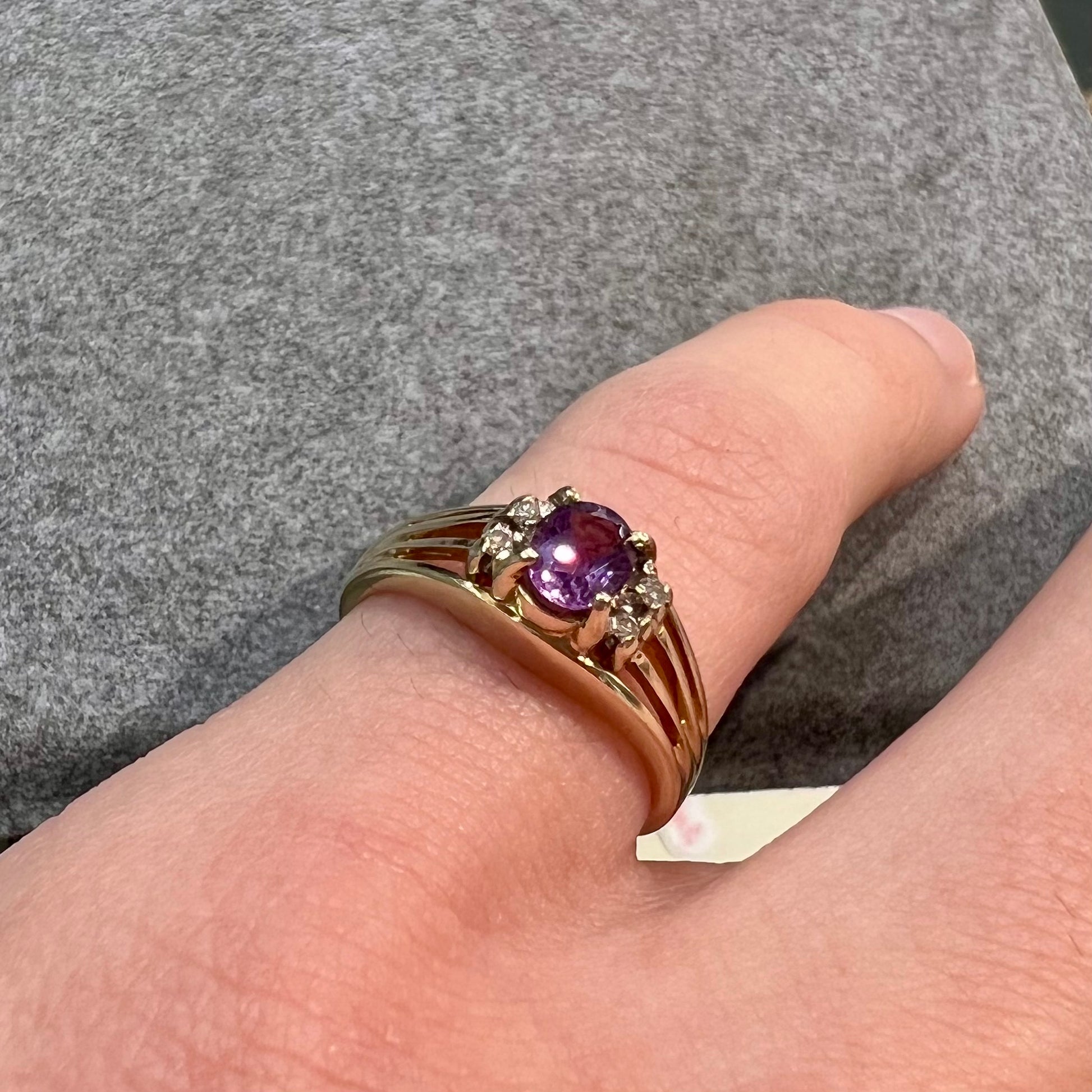 A ladies split shank gold ring set with an oval cut amethyst and round brilliant diamond accents.