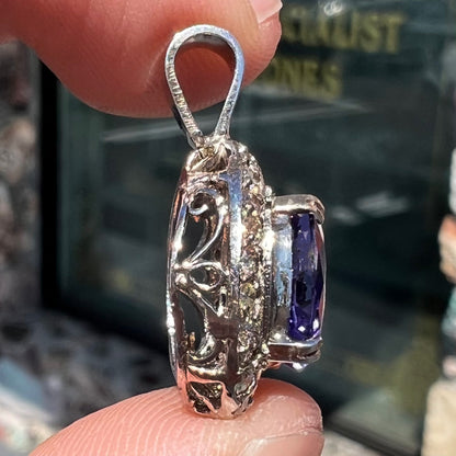 A ladies' 14kt white gold tanzanite and diamond halo pendant.  The sides of the pendant have filigree.