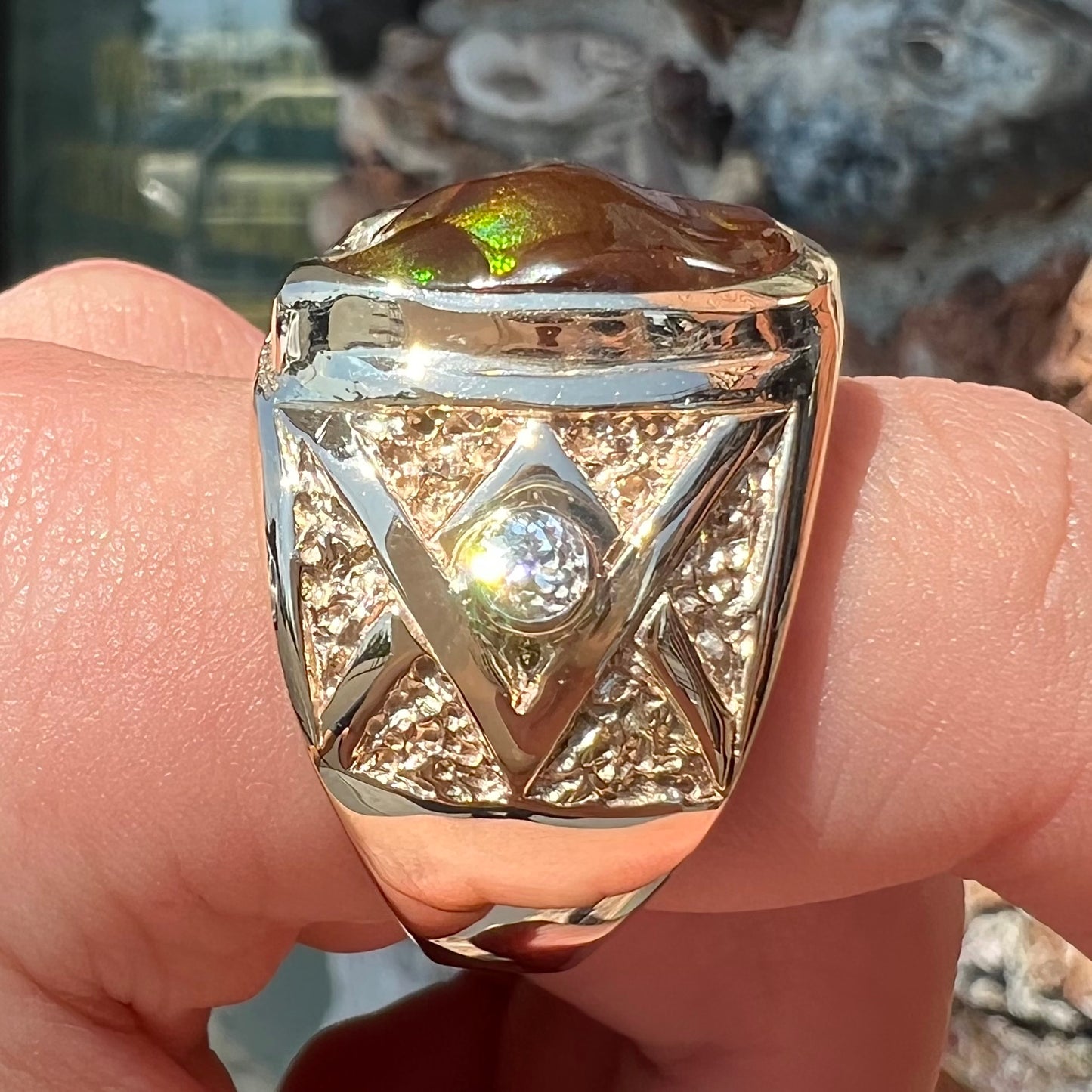 A men's solid yellow gold fire agate and diamond ring.  The fire agate displays predominantly red and green.