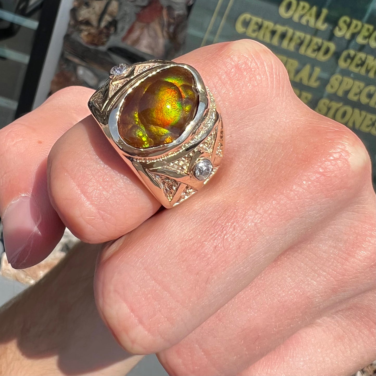 A men's solid yellow gold fire agate and diamond ring.  The fire agate displays predominantly red and green.