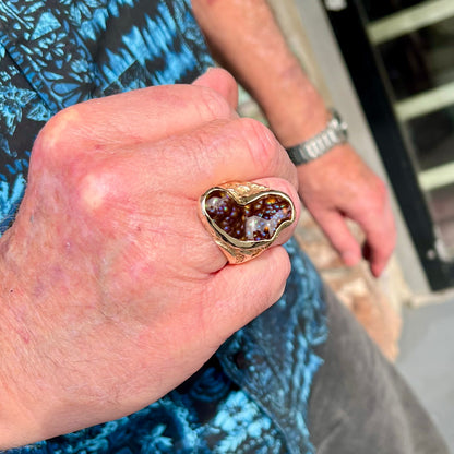 A men's Deer Creek fire agate solitaire ring cast in yellow gold.  The stone is predominantly purple.