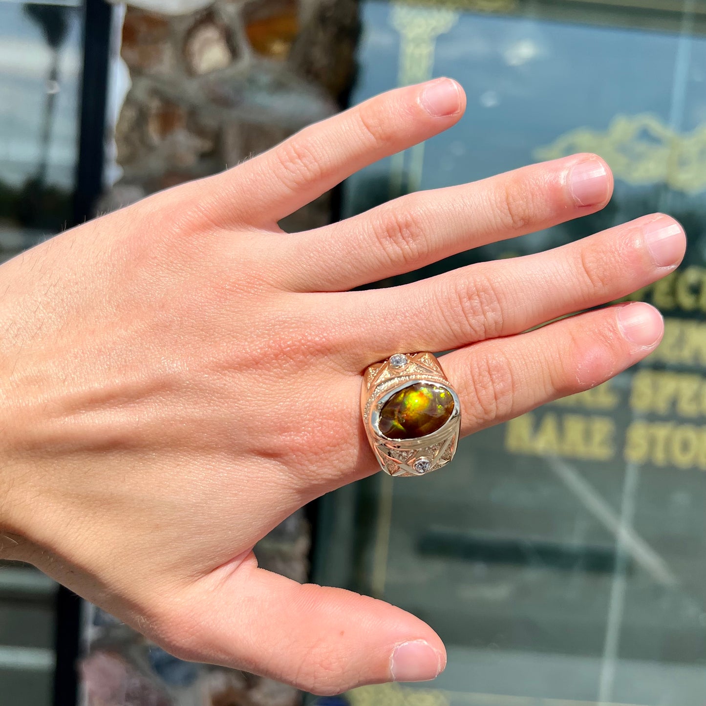 A men's solid yellow gold fire agate and diamond ring.  The fire agate displays predominantly red and green.