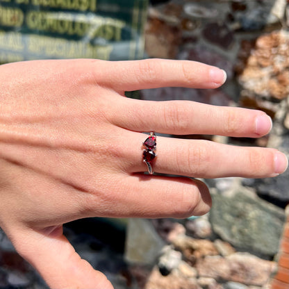 A sterling silver ring set with two faceted heart shape red almandine garnet stones.