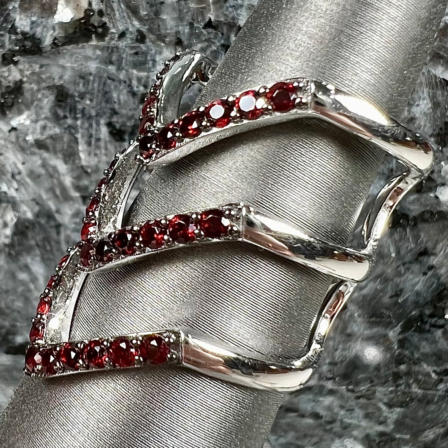 A sterling silver ring pave set with round almandine garnet stones.  The piece appears to be three rings in one.