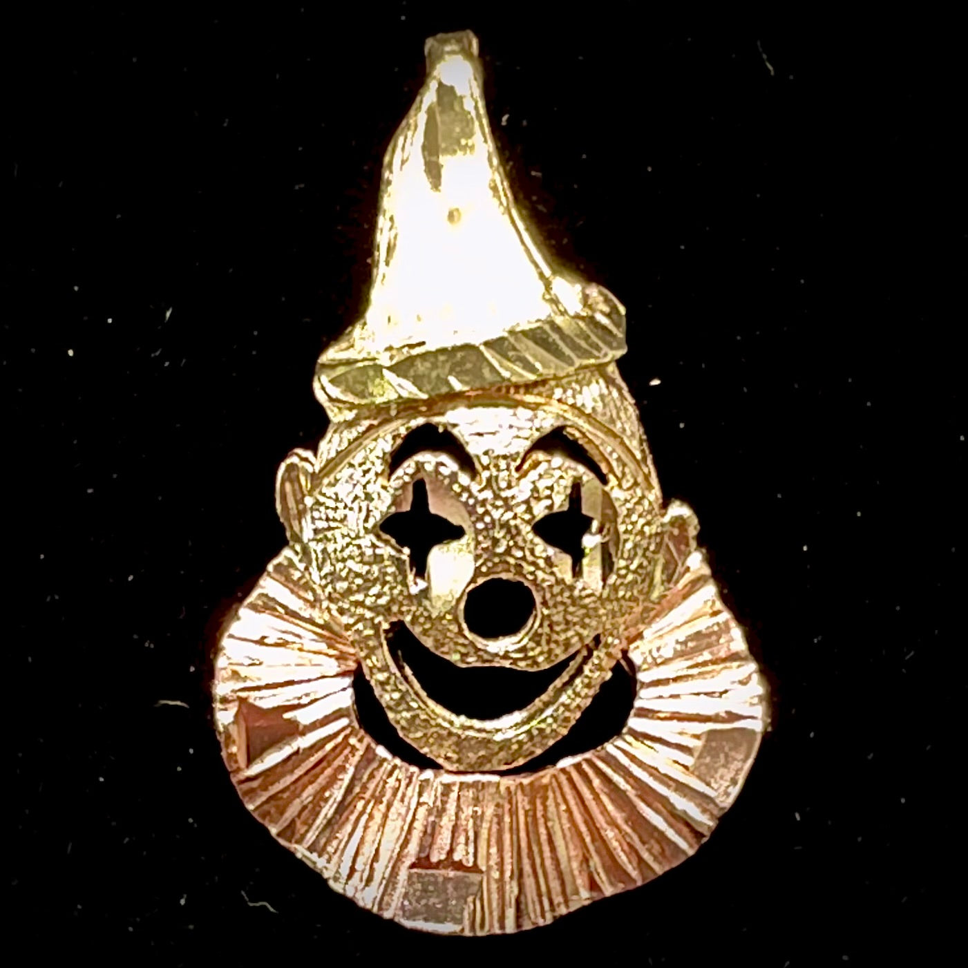 A small gold clown pendant charm.  The clown's face and hat are yellow gold, and his neck frills are rose gold.