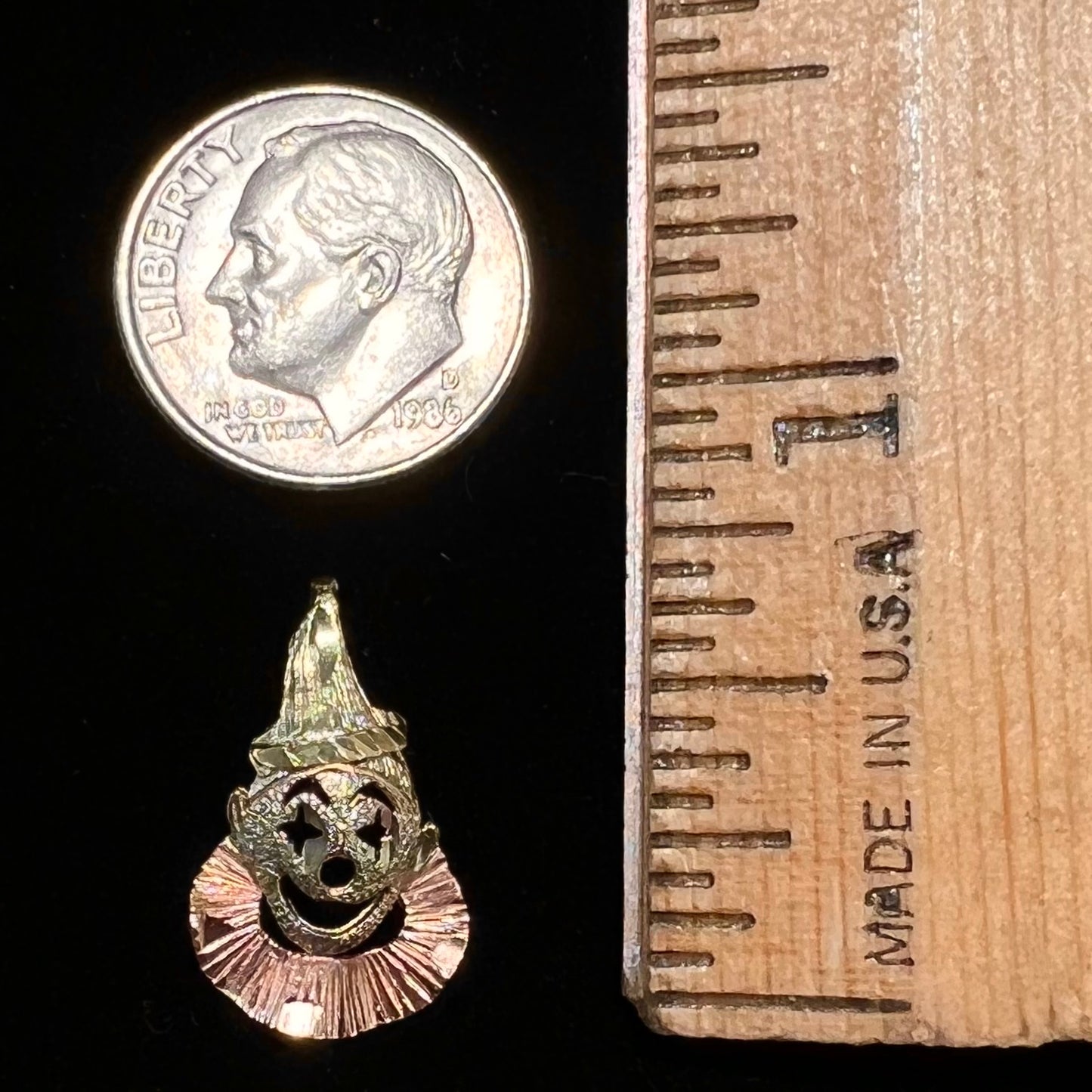 A small gold clown pendant charm.  The clown's face and hat are yellow gold, and his neck frills are rose gold.