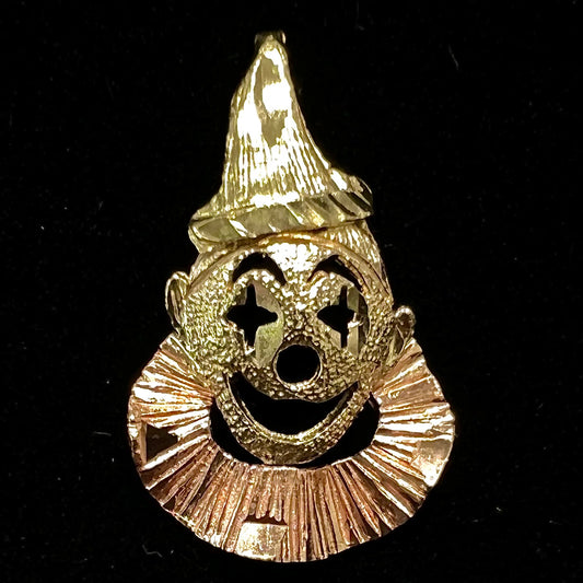 A small gold clown pendant charm.  The clown's face and hat are yellow gold, and his neck frills are rose gold.