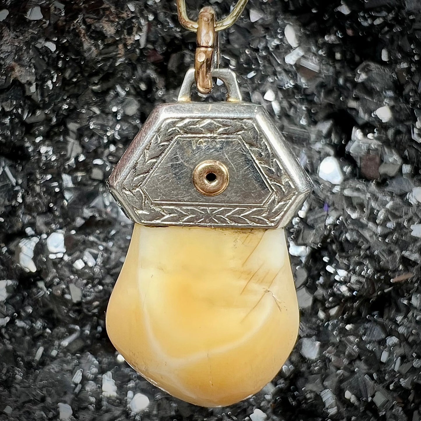 An elk tooth that has been fashioned into a blue enameled gold pendant.  There is a decorative elk head cast in yellow gold set on the piece.