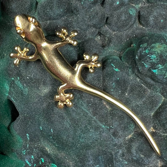 A solid yellow gold gecko lizard pendant with a hidden bail.