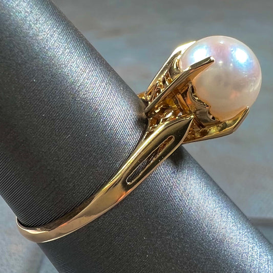 Round white pearl with pink overtones set in a vintage 18k yellow gold ring.