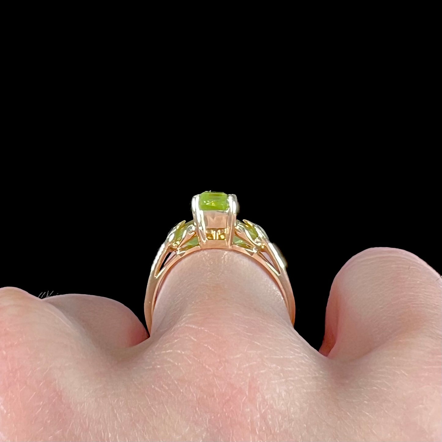 A ladies' three stone peridot ring in yellow gold.  The center stone is emerald cut, and the side stones are pear shaped.