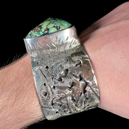 A men's sterling silver cuff bracelet infused with copper and set with a green turquoise stone from Carico Lake, Nevada.