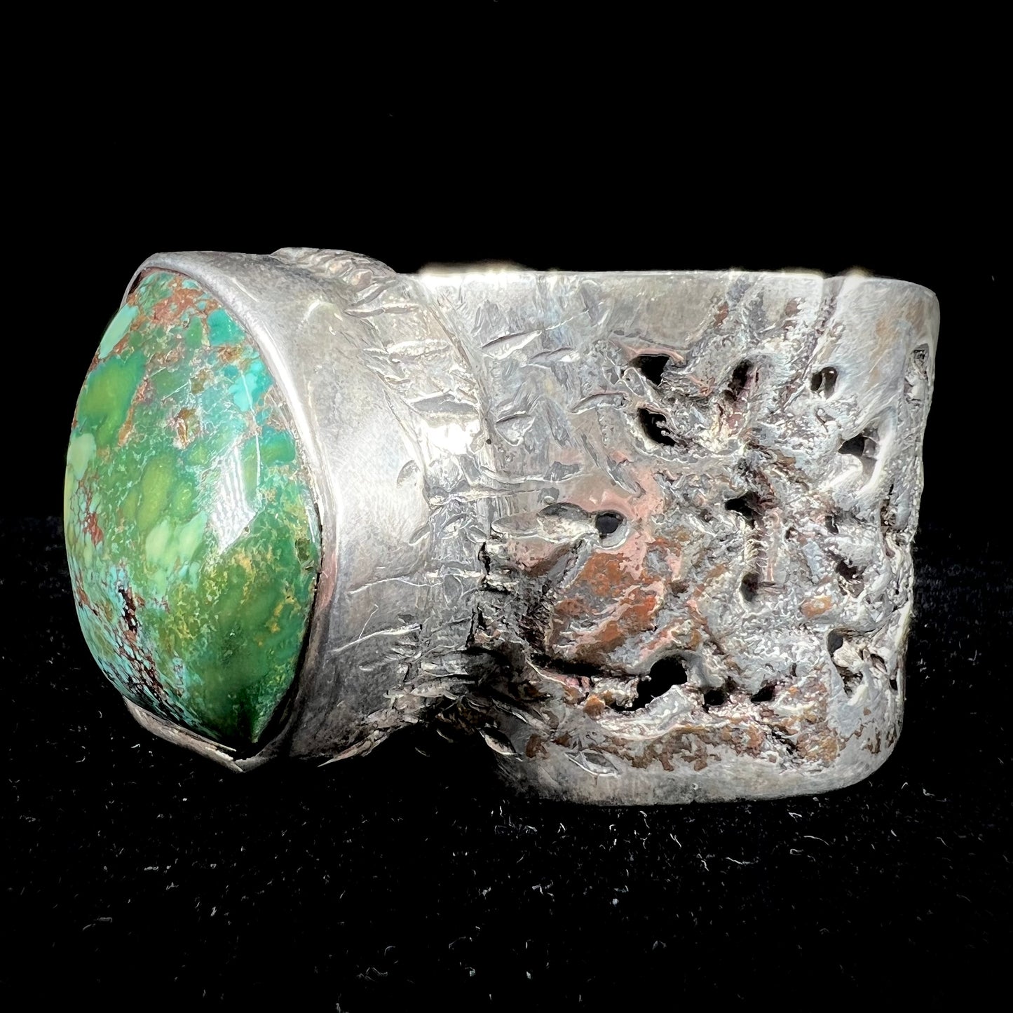 A men's sterling silver cuff bracelet infused with copper and set with a green turquoise stone from Carico Lake, Nevada.