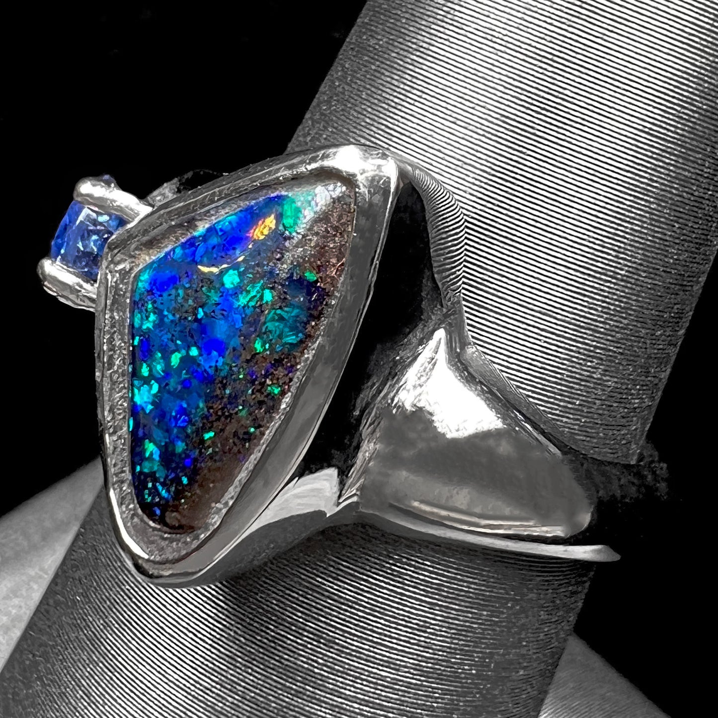 A ladies' white gold ring set with Australian black boulder opal and pear shape blue sapphire.