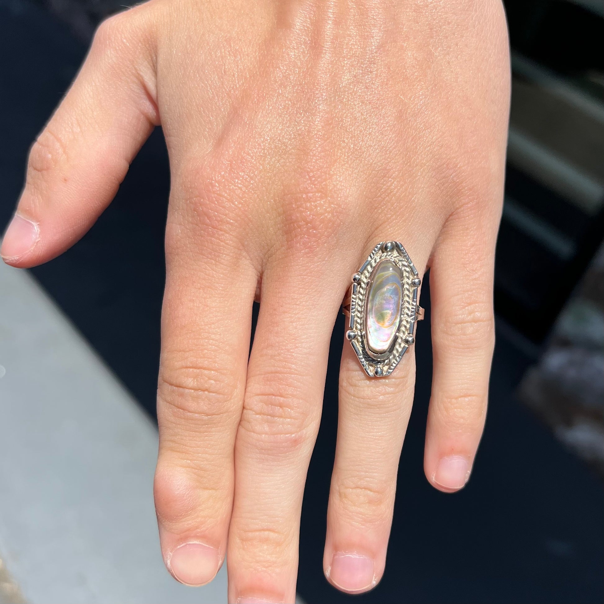 A Southwest style sterling silver ring set with a pink, oval cabochon cut mother of pearl shell.