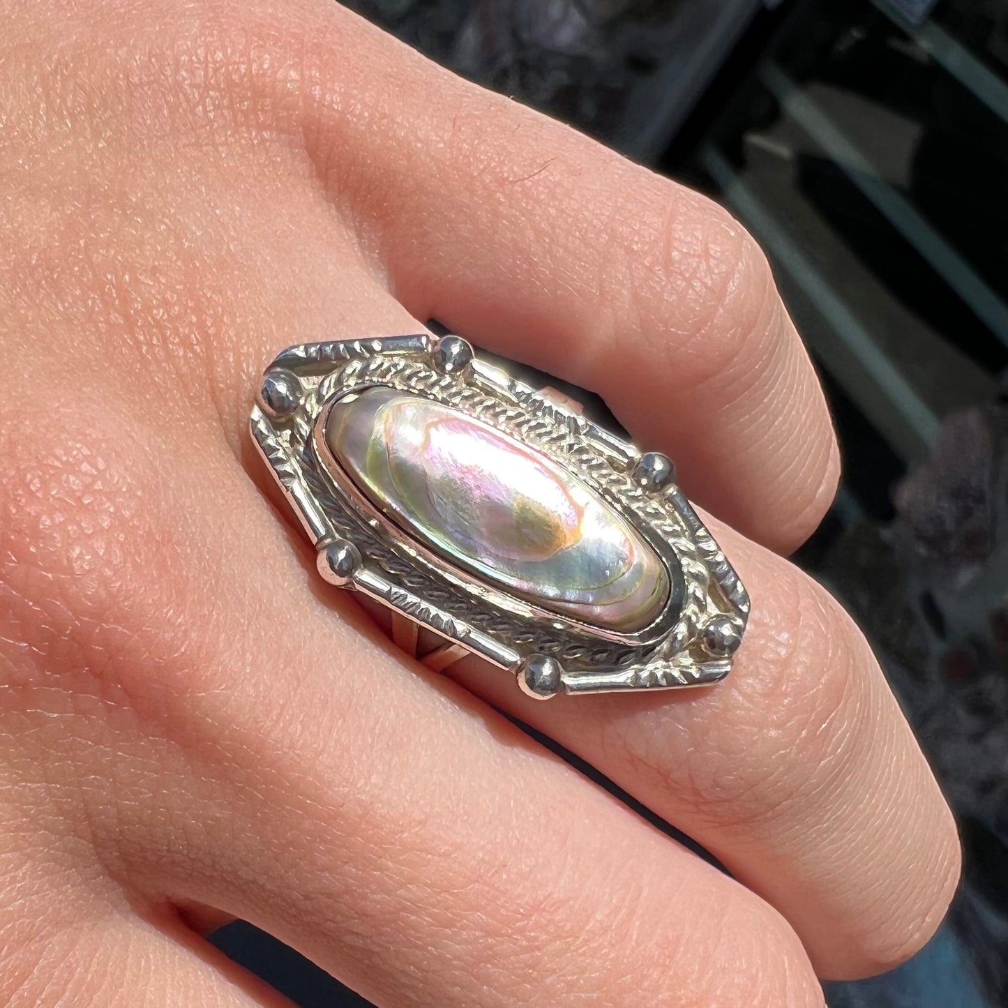 A Southwest style sterling silver ring set with a pink, oval cabochon cut mother of pearl shell.