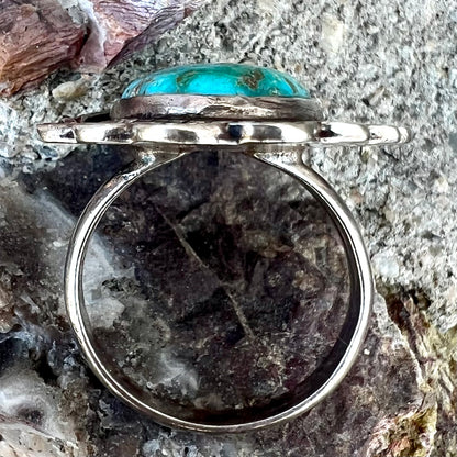 A sterling silver Navajo style ring.  The ring is set with a turquoise stone from Pilot Mountain.  There is a feather decoration next to the stone.