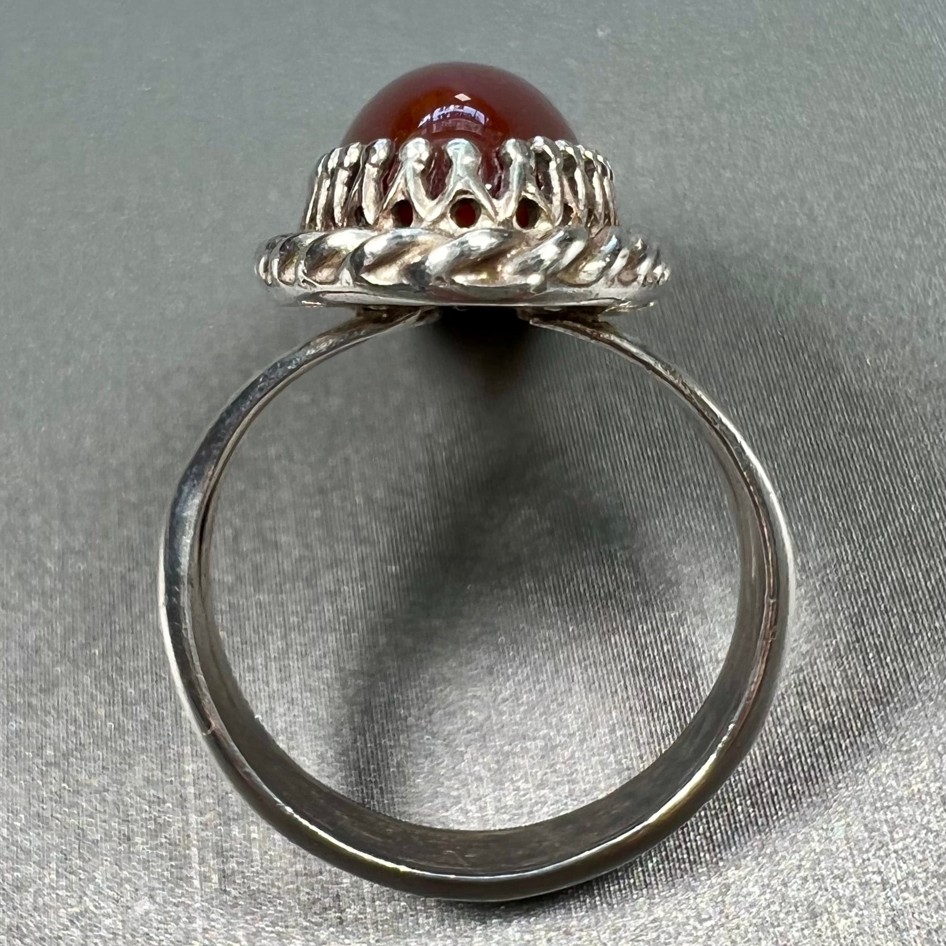 A split shank silver ring set with a brown sard stone in a rope bezel with small prongs.