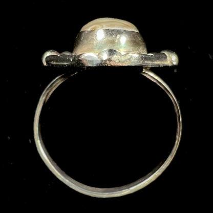 A Southwest style sterling silver ring set with a pink, oval cabochon cut mother of pearl shell.