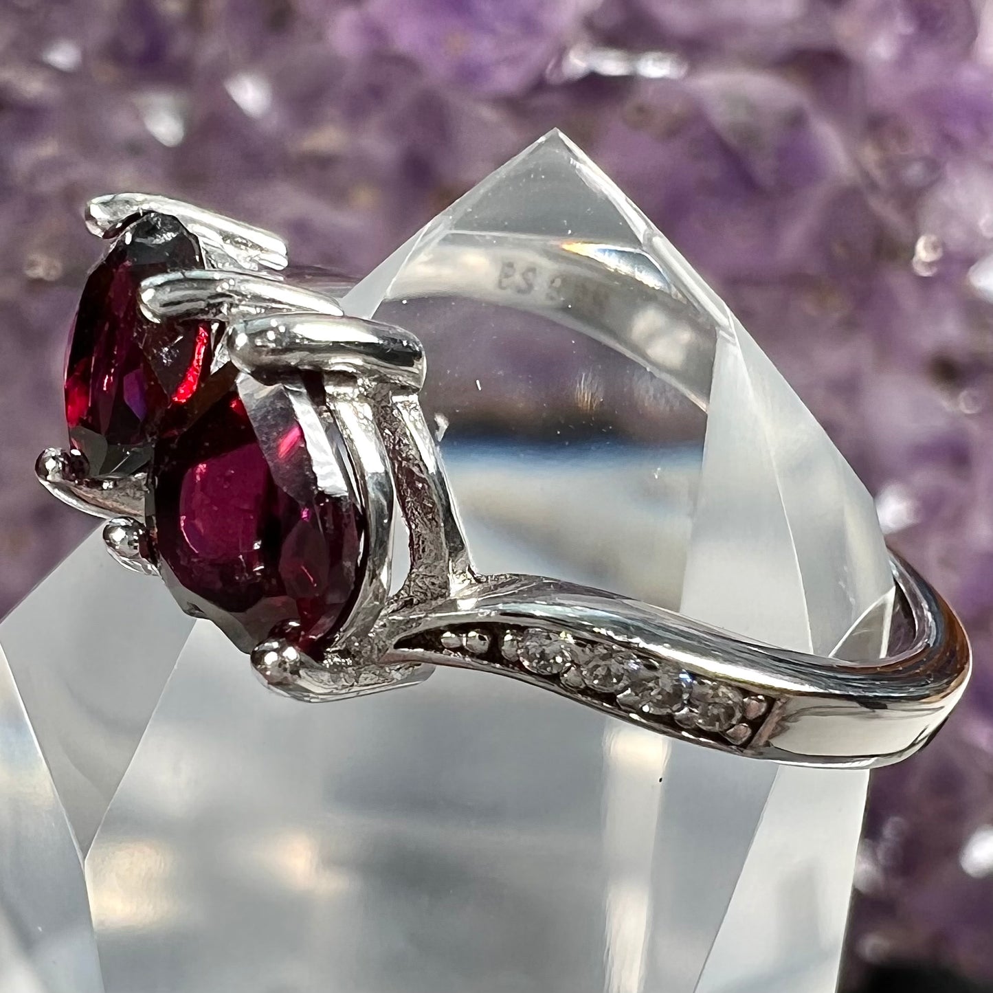 A sterling silver ring set with two faceted heart shape red almandine garnet stones.