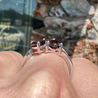 A sterling silver ring set with two faceted heart shape red almandine garnet stones.