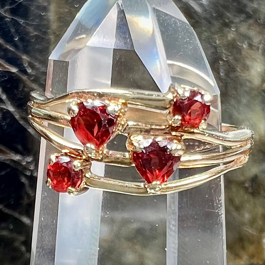 A yellow gold multishank ring set with two heart shape and two round cut red garnets.