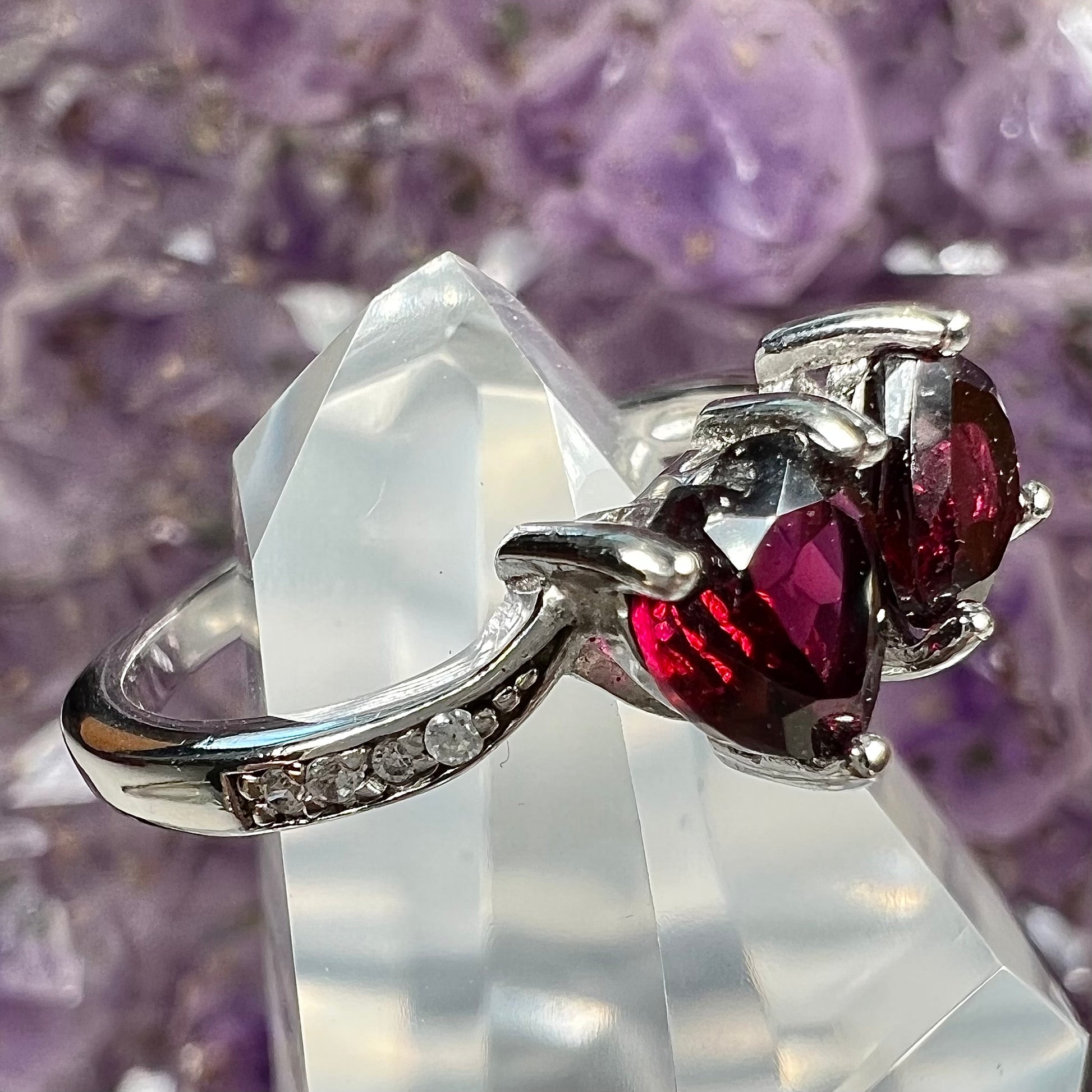 A sterling silver ring set with two faceted heart shape red almandine garnet stones.