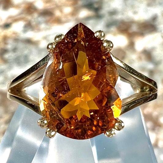 A gold split Euro shank solitaire ring set with an orange pear shape hessonite garnet stone.