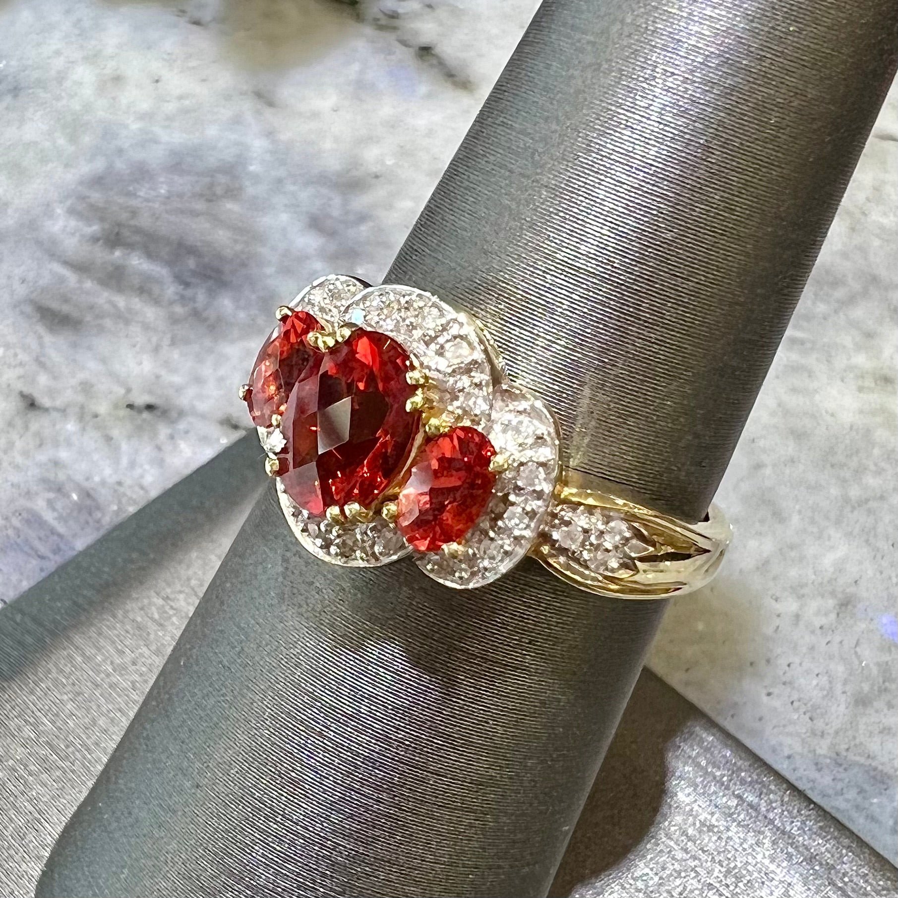 Past, present, future style red andesine feldspar and diamond halo ring cast in 14kt yellow gold.