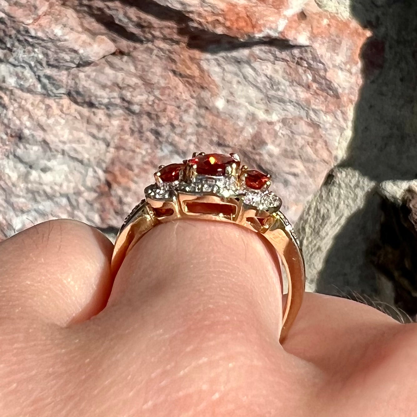 Past, present, future style red andesine feldspar and diamond halo ring cast in 14kt yellow gold.