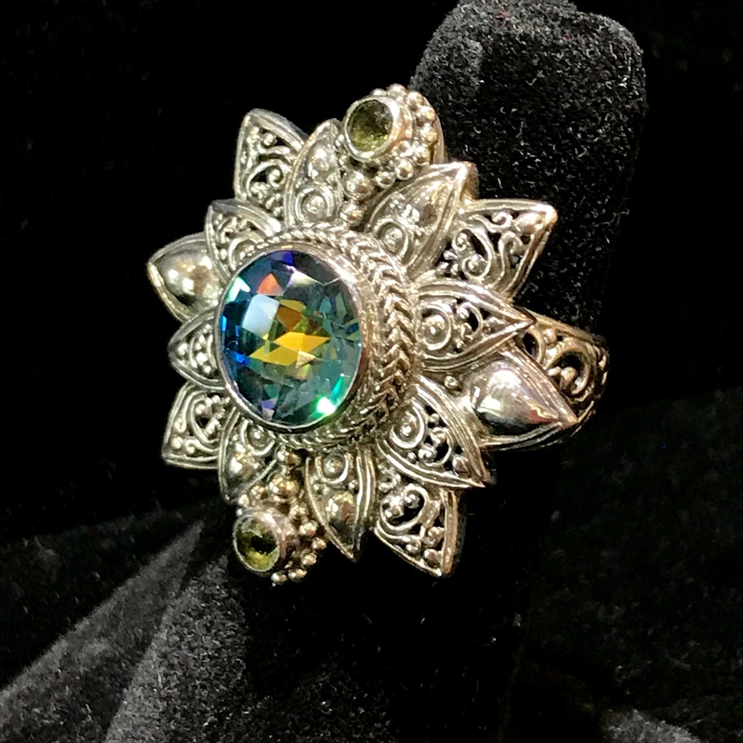 Sterling silver filigree flower design bezel set with synthetic multicolored gemstones.