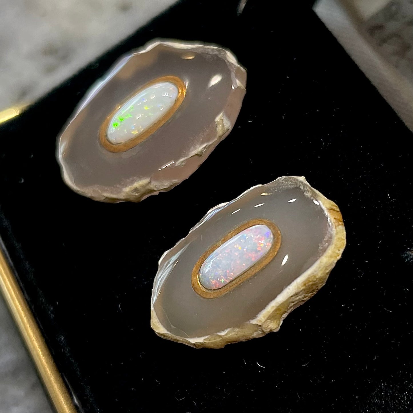 Earrings featuring oval cut white crystal opal cabochons set in slices of polished agate with yellow gold bezels.
