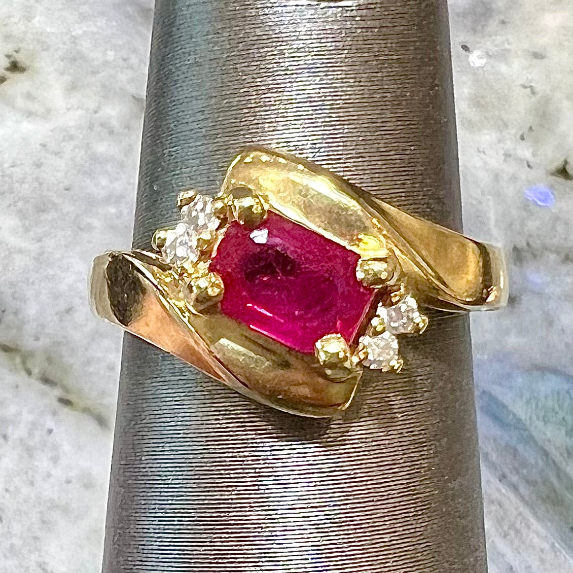 Emerald cut Burma ruby and diamond ring set in 14 karat yellow gold.