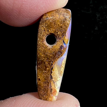 A polished, drilled pipe boulder opal bead.