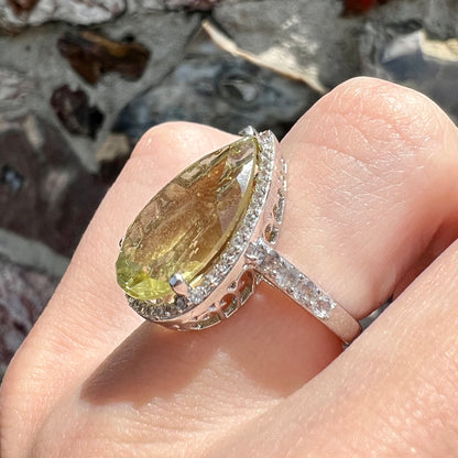 A pear shape lemon quartz set in a sterling silver and white topaz halo ring.