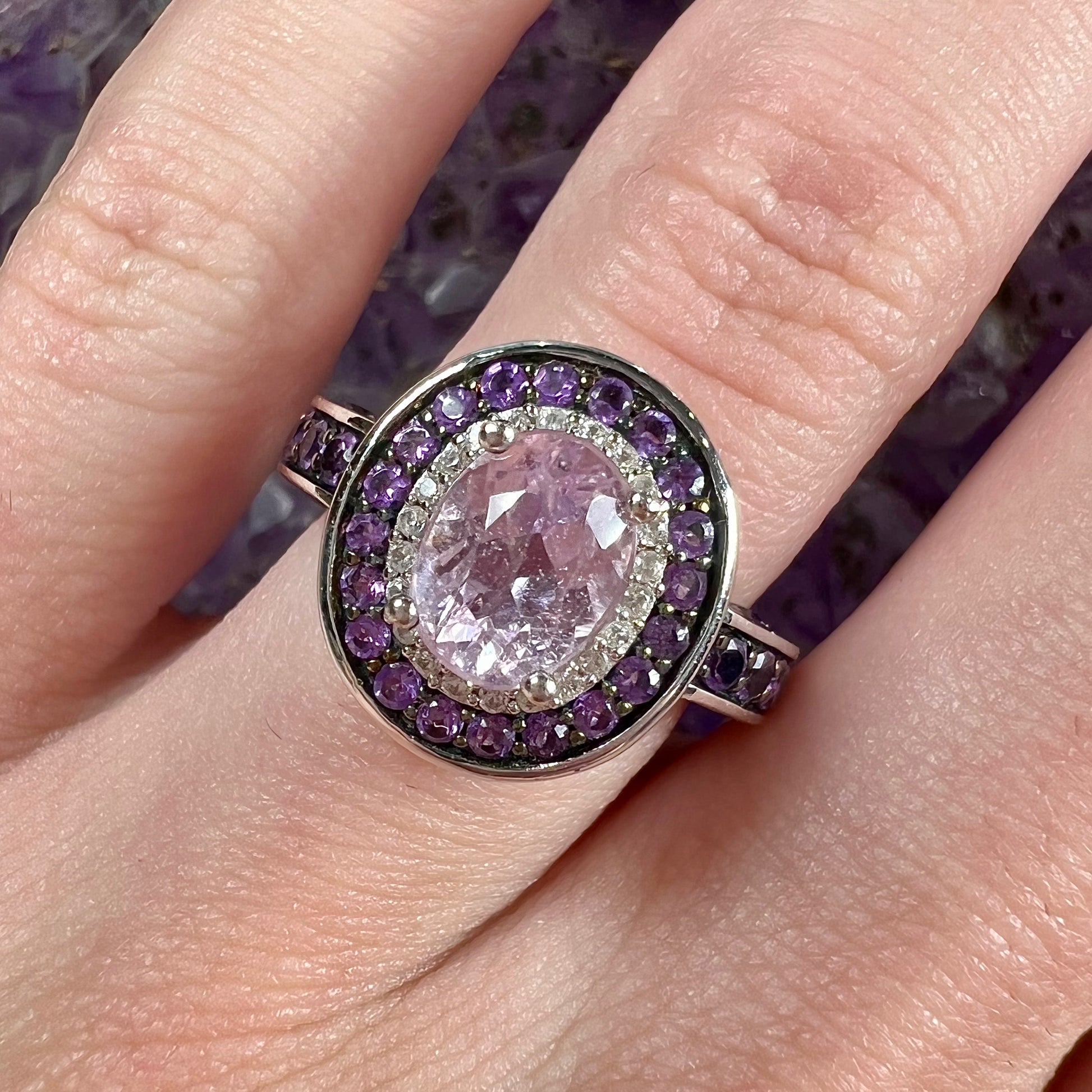 A sterling silver oval cut kunzite ring set with a double halo of round cut CZ and amethysts.